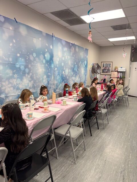 Young dancers seated at a long table for a tea party at the studio